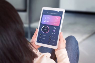 Akıllı ev kontrol otomasyon app kavramı. Kadın kullanım tablet modern düz ile app-e doğru kontrol oturma odası sıcaklık, havalandırma, aydınlatma tasarımı.