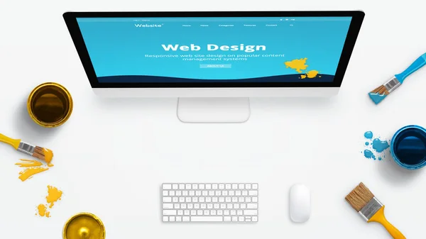 Concept of a modern web design studio with color brushes and color boxes on a clean desk. Modern web site on computer display painted with colors.