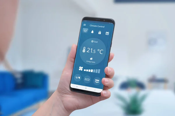 Modern climate control app interface on a smartphone in hand. Concept of simple temperature control and auto heating.