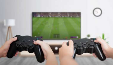Boys play soccer on the gaming console on a large TV in the room. The concept of fun and gaming for friends. clipart