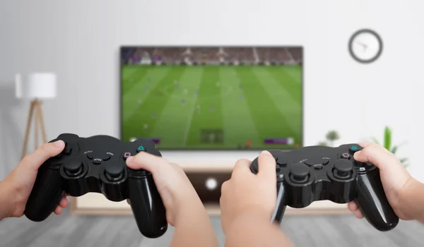 Boys play soccer on the gaming console on a large TV in the room. The concept of fun and gaming for friends.