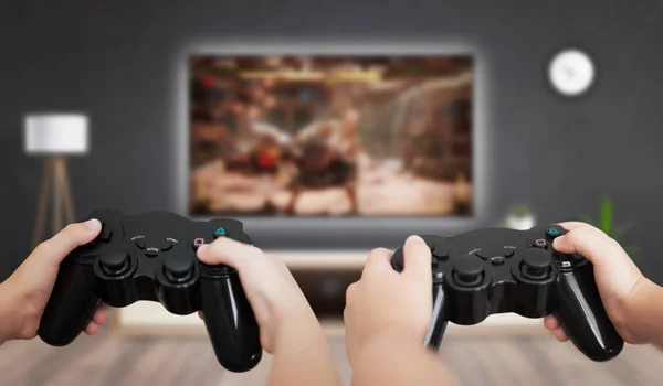 Gaming in living room concept. Two boys holding gamepad and play console game on TV.