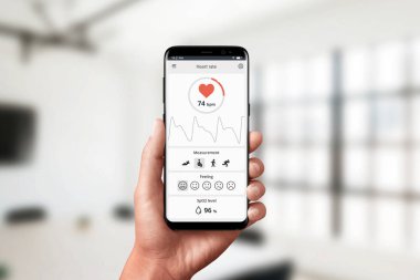 Elinde akıllı telefonda kalp atış hızı uygulamasını ölçme. Ofiste ölçme kavramı. Modern, düz tasarım uygulaması konsepti.