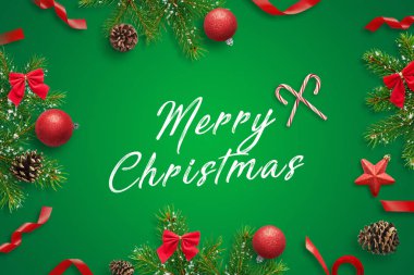 Mutlu Noeller tebrik kartı. Yeşil yüzeyde Noel süslemeleri ve köknar dalları. Düz konum, üst görünüm bileşimi.