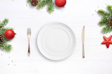 Boş tabak, çatal ve yılbaşı süslemeleriyle çevrili bıçak. Üst manzara, düz yatış. Noel yemeği konsepti.