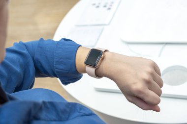 Kadın bileğinde akıllı saat. Model için boş ekran, uygulama promosyonu. Ofis masası arka planda. Yakın plan..