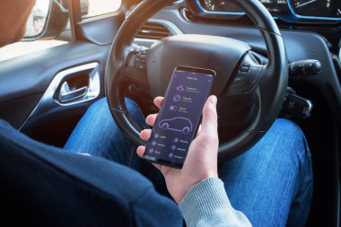 Sürücünün elindeki akıllı telefondaki mobil uygulamanın araba bilgileri.