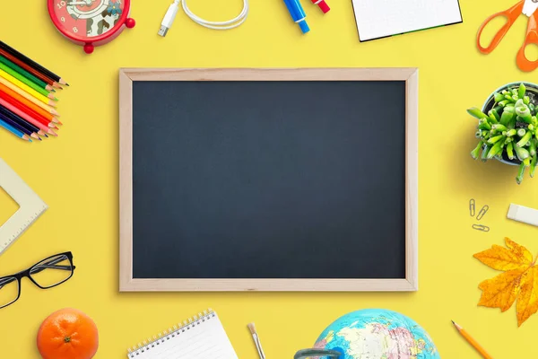 プロモーションテキストのための学校用品に囲まれた空の黒板 黄色の作業机の上のビューの組成 — ストック写真
