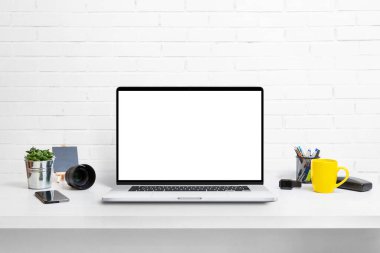 Model, uygulama veya web sitesi promosyonu için izole ekranı olan çalışma masasındaki modern dizüstü bilgisayar. Kahve ve bitkiyle dolu temiz bir masa.