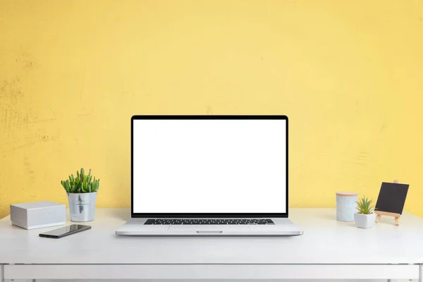 Laptop computer mockup on office desk with yellow wall in background. Isolated screen in white for web site design promotion
