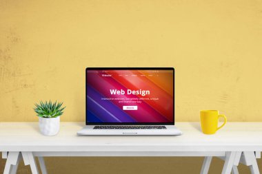 Web tasarım web sitesi konsepti. Masada dizüstü bilgisayar, yanında bitki ve kahve fincanı olsun.