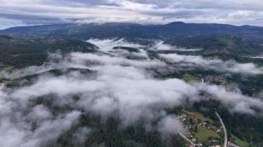 Sisli dağ vadisinin manzarası bulutların altındaki gizli köy yolları soldan sağa sinematik hareketlerle çekiliyor.