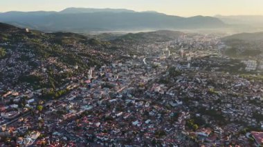 Saraybosna 'nın parlayan gökyüzü ve şehir manzarasıyla gün batımında çekilen panoramik drone görüntüleri