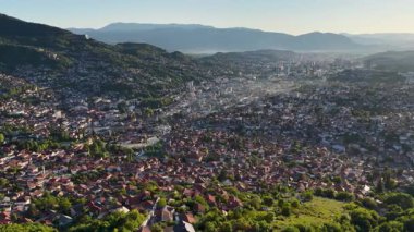 Saraybosna 'nın arka planında dağlar olan panoramik hava aracı görüntüsü, sola doğru yavaşça hareket eden kamera