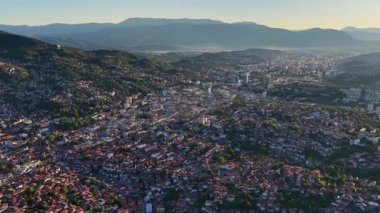 Saraybosna 'nın yukarıdan çekilmiş sinematik görüntüleri, dağ manzaralı şehir manzarası, sola hareket eden kamera