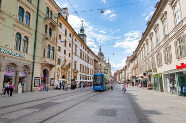 Graz, Avusturya 26 Haziran 2024 Herrengasse caddesinden geçen mavi tramvay tarihi bina ve dükkanlarla dolu.