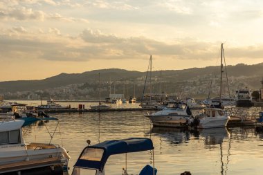 Kavala, Yunanistan. 10 Temmuz 2024. Kavala Limanı 'nda sakin deniz suyuna yansıyan balıkçı tekneleri ve yatlarla akşam atmosferi