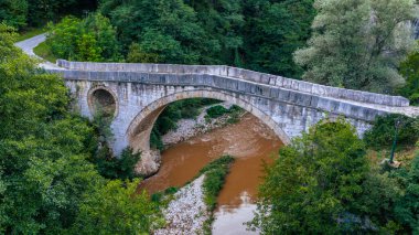 Yoğun yeşil ormanlarla çevrili Miljacka Nehri 'ni geçen Kozja Cuprija taş köprüsünün ayrıntılı görüntüsü