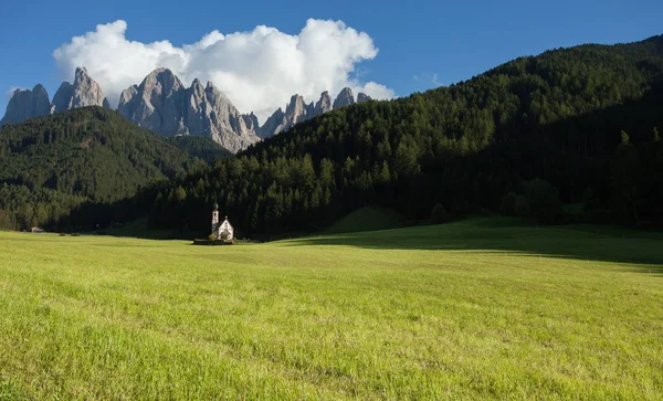 Igreja pequena de St. Johann entre um prado verde largo em St. Magdalena, Val di Funes — Fotografia de Stock