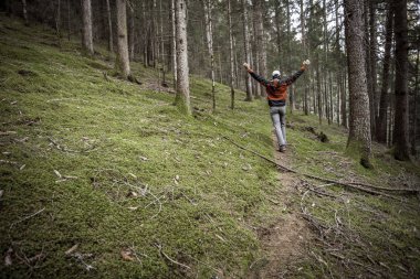 Bulutlu bir günde ormanda tek başına yürüyen bir yürüyüşçü.