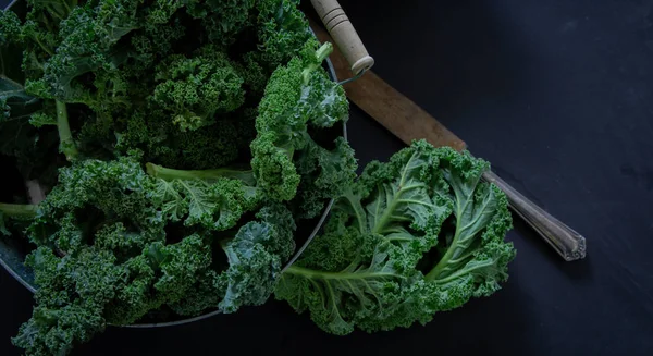 Green Kale and knife on black background top view on daylight superfood vegetables Still life
