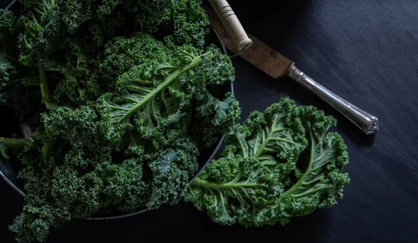 Green Kale and knife on black background top view on daylight superfood vegetables Still life
