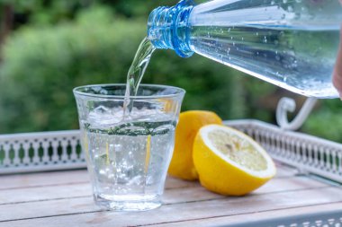 İnsanlar gün ışığında şişeden gelen suyla bardağı doldurur. 