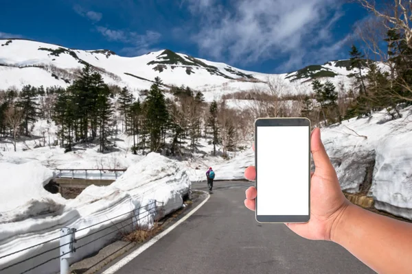 hand hold mobile phone with a road of snow wall japan alps mount