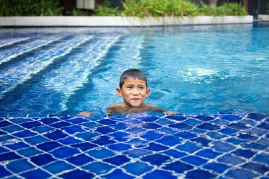 sevimli küçük çocuk mutlu oyun hissediyorum ve yüzme havuzunda yüzme , güneşli gün ve yumuşak odak.