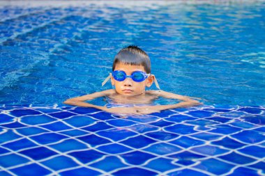 sevimli küçük çocuk mutlu oyun hissediyorum ve yüzme havuzunda yüzme , güneşli gün ve yumuşak odak.