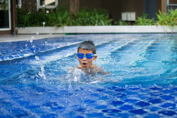 sevimli küçük çocuk mutlu oyun hissediyorum ve yüzme havuzunda yüzme , güneşli gün ve yumuşak odak.
