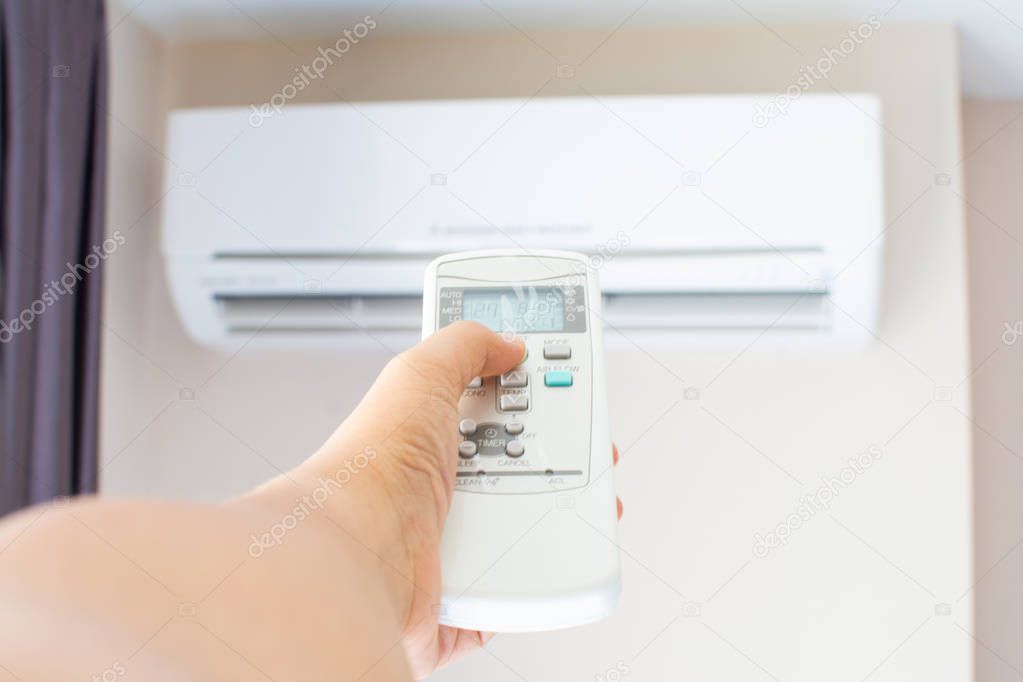 human hand press on remote control of Air Conditioner with hot w
