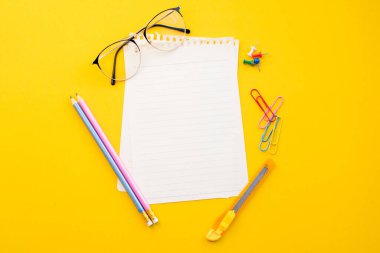 Renk arkaplanına dizüstü gözlük ve kalem boş kağıt.