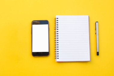 Sarı arkaplanda boş kalem ve akıllı telefon kağıdı
