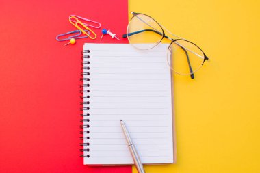 Renk arkaplanına dizüstü gözlük ve kalem boş kağıt.