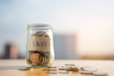Para sikkesi ahşap masa üzerinde ve bulanık arkaplan ile SAVE metin.