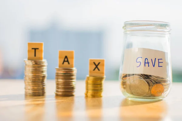 Tahta masa üzerinde para sikkesi ve metin Vergi Tasarruf bulanık arkaplan.