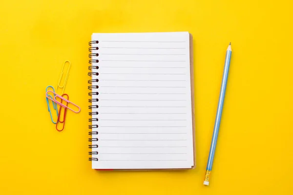 Renk arkaplanına dizüstü gözlük ve kalem boş kağıt.