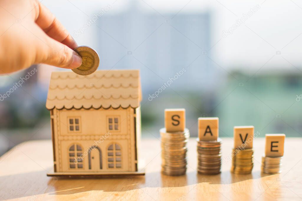 coin of money on wooden table and miniature home with blur background.