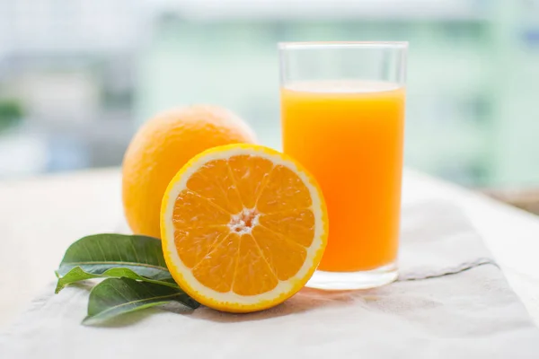 orange and orange juice with leaf on wooden table at sunny day. soft focus.