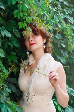 Açık bej güzel kız elbise içinde yeşil yaprakları yakın çekim