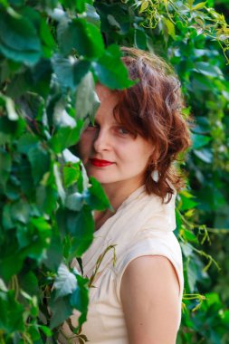 Açık bej güzel kız elbise içinde yeşil yaprakları yakın çekim