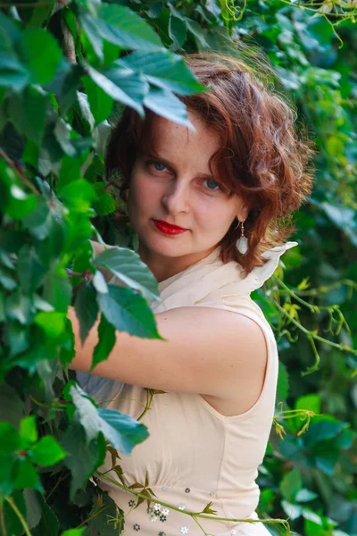 Açık bej güzel kız elbise içinde yeşil yaprakları yakın çekim