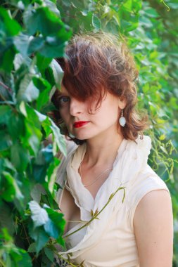 Açık bej güzel kız elbise içinde yeşil yaprakları yakın çekim