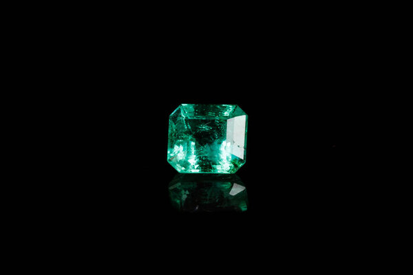 Macro mineral Emerald gemstone faceted on black background close up
