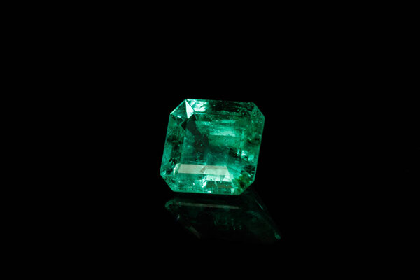 Macro mineral Emerald gemstone faceted on black background close up