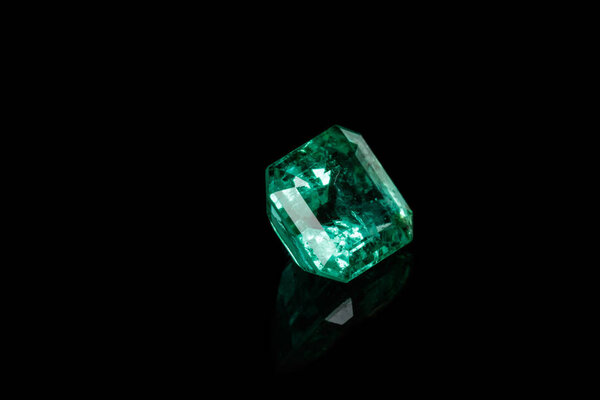 Macro mineral Emerald gemstone faceted on black background close up