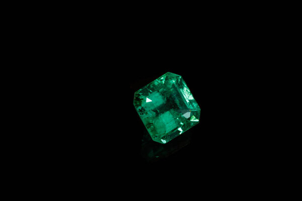 Macro mineral Emerald gemstone faceted on black background close up