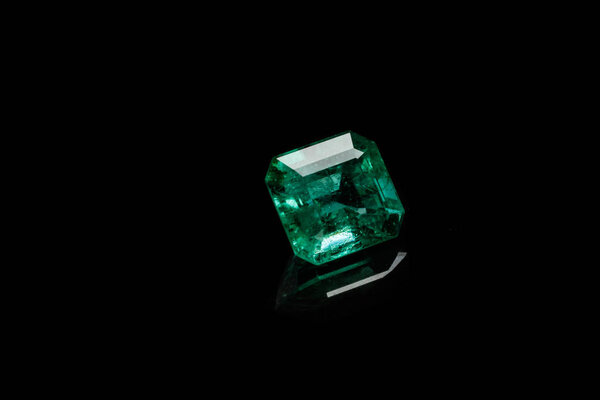 Macro mineral Emerald gemstone faceted on black background close up