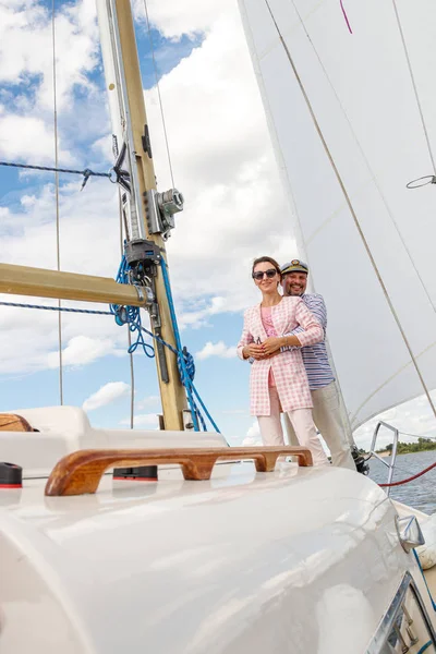 sailor man in a cap with a girl on a boat under sail against the